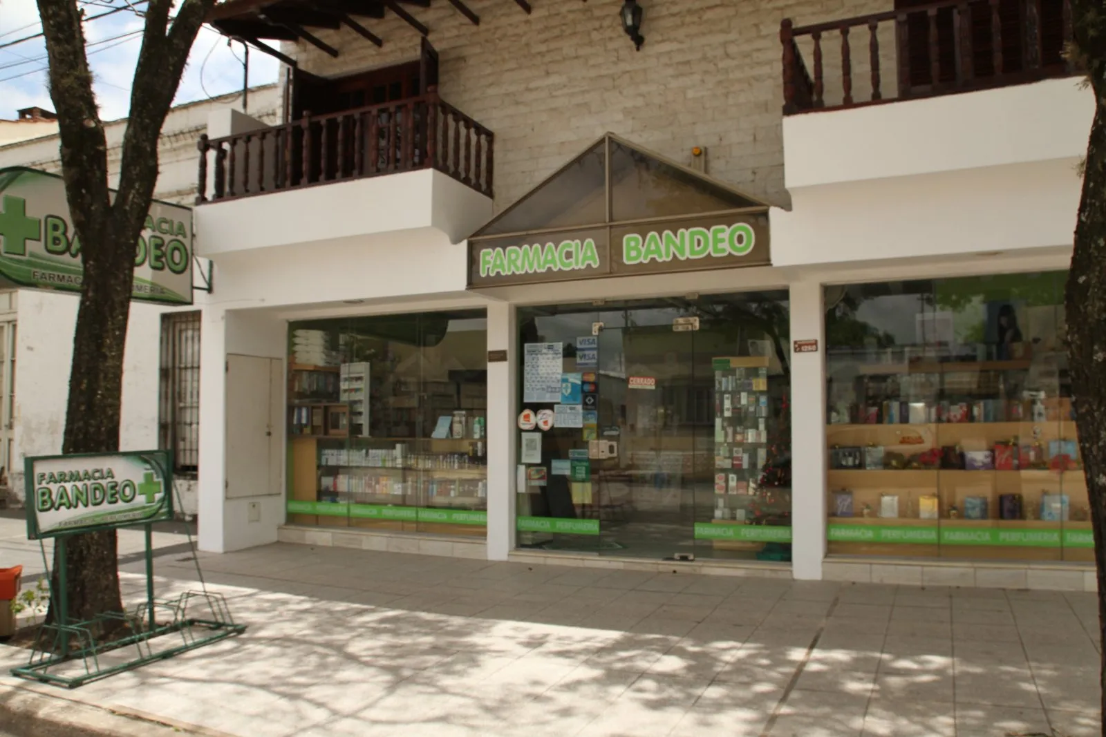 Fachada de Farmacia Bandeo con su cartel verde y la vidriera de perfumería